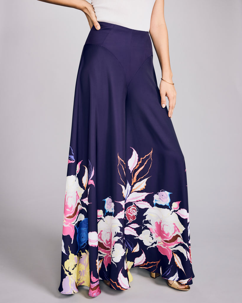 Ultra wide-legged trousers from D2Line are crafted from a rich aubergine purple luxury polyester with floral patterning at the bottom in shades of pink, blue, white, purple and chartreuse&nbsp;