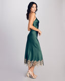 Curve hugging Matinee midi slip dress from Gilda & Pearl is crafted from a decadent emerald green silk with gold lace at the hem