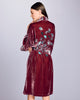 Knee-length Nikko robe from Karma on the Rocks is crafted from a decadent burgundy red silk velvet with a custom gingko embroidery in shades of teal and silver at the shawl collar, cuffs and back